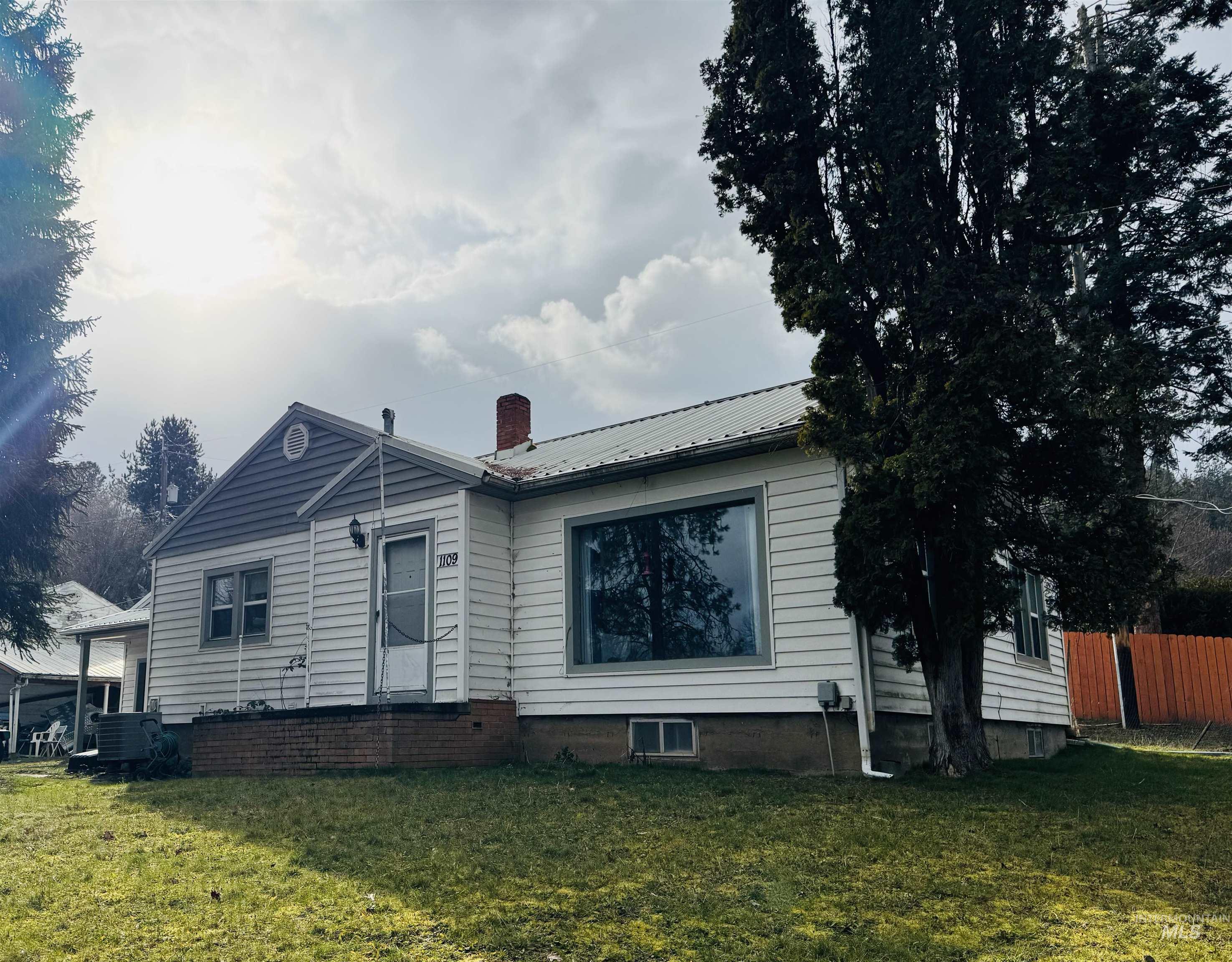 View of front facade featuring a metal roof and a chimney