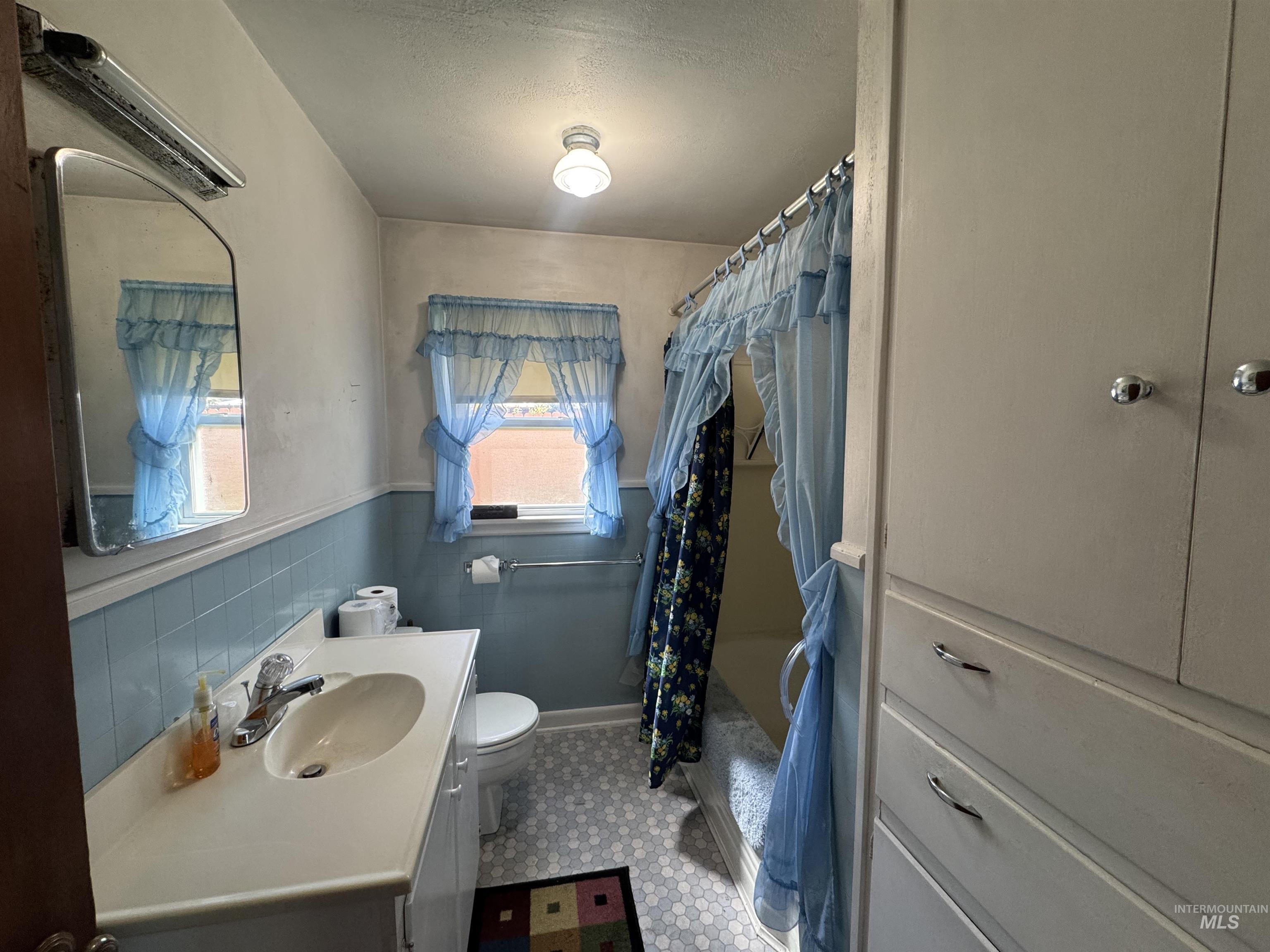 1109 3rd Street Kamiah, ID 83536 - Photo 12 of 21 Full bathroom featuring vanity, shower / bath combo, light floors, a wainscoted wall, and tile walls