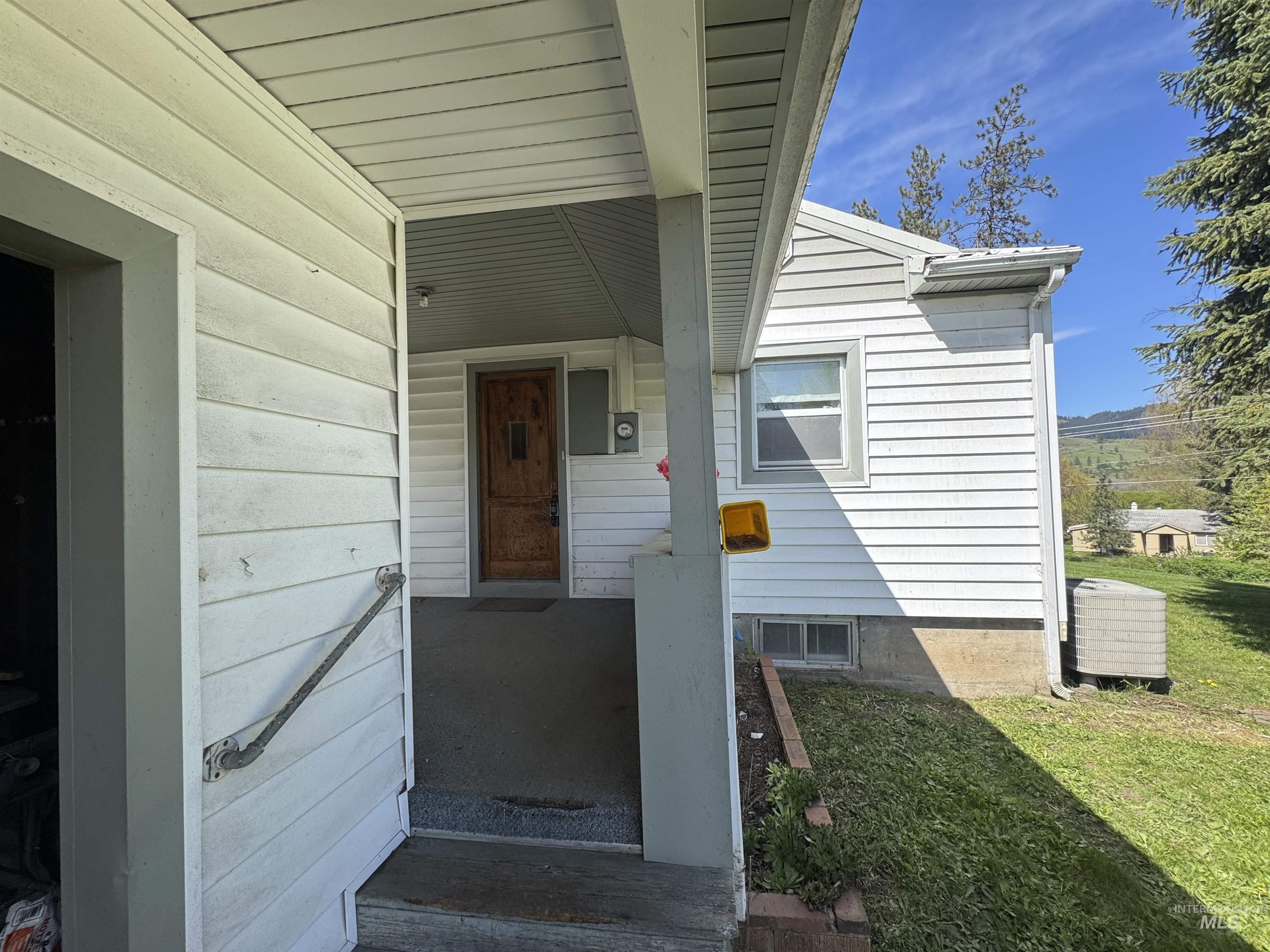 1109 3rd Street Kamiah, ID 83536 - Photo 3 of 21 Covered front porch entry with wood-finish door, white siding exterior, and a single window