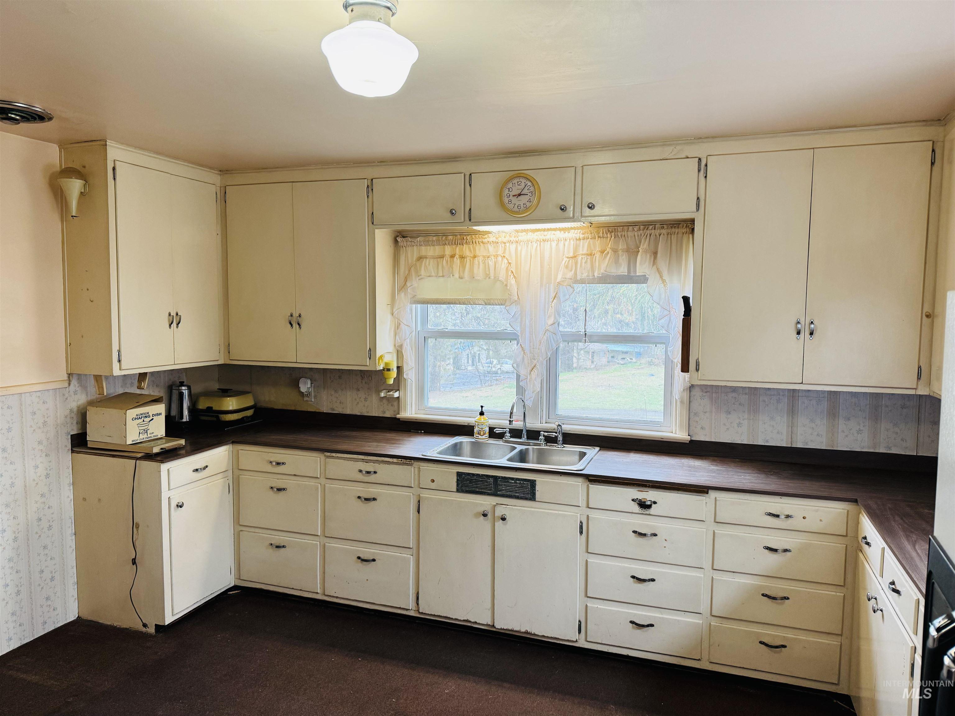1109 3rd Street Kamiah, ID 83536 - Photo 6 of 17 Kitchen featuring wallpapered walls, cream cabinets, and dark countertops