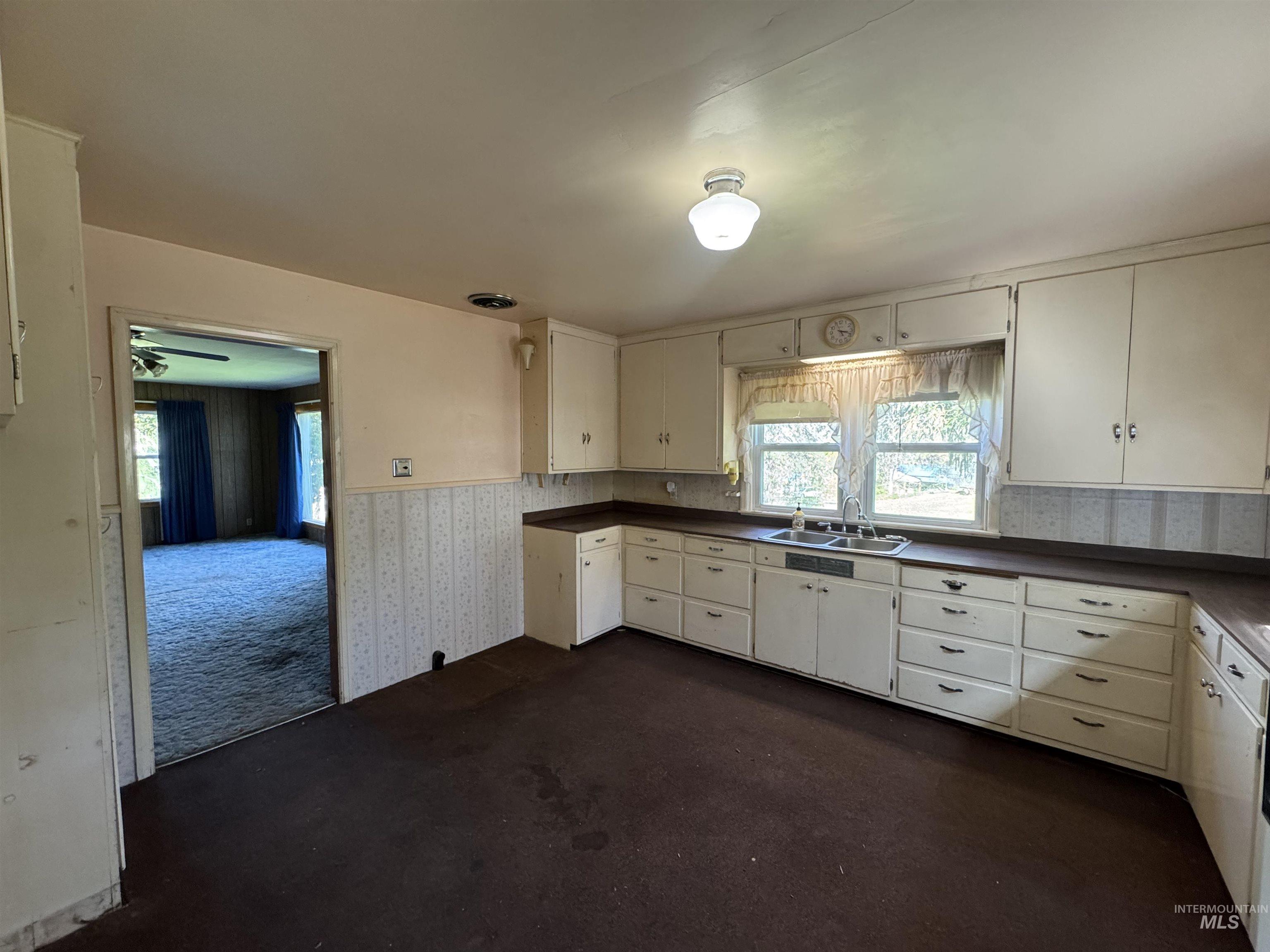 1109 3rd Street Kamiah, ID 83536 - Photo 7 of 21 Kitchen with dark colored carpet, dark countertops, wallpapered walls, plenty of natural light, and white cabinets