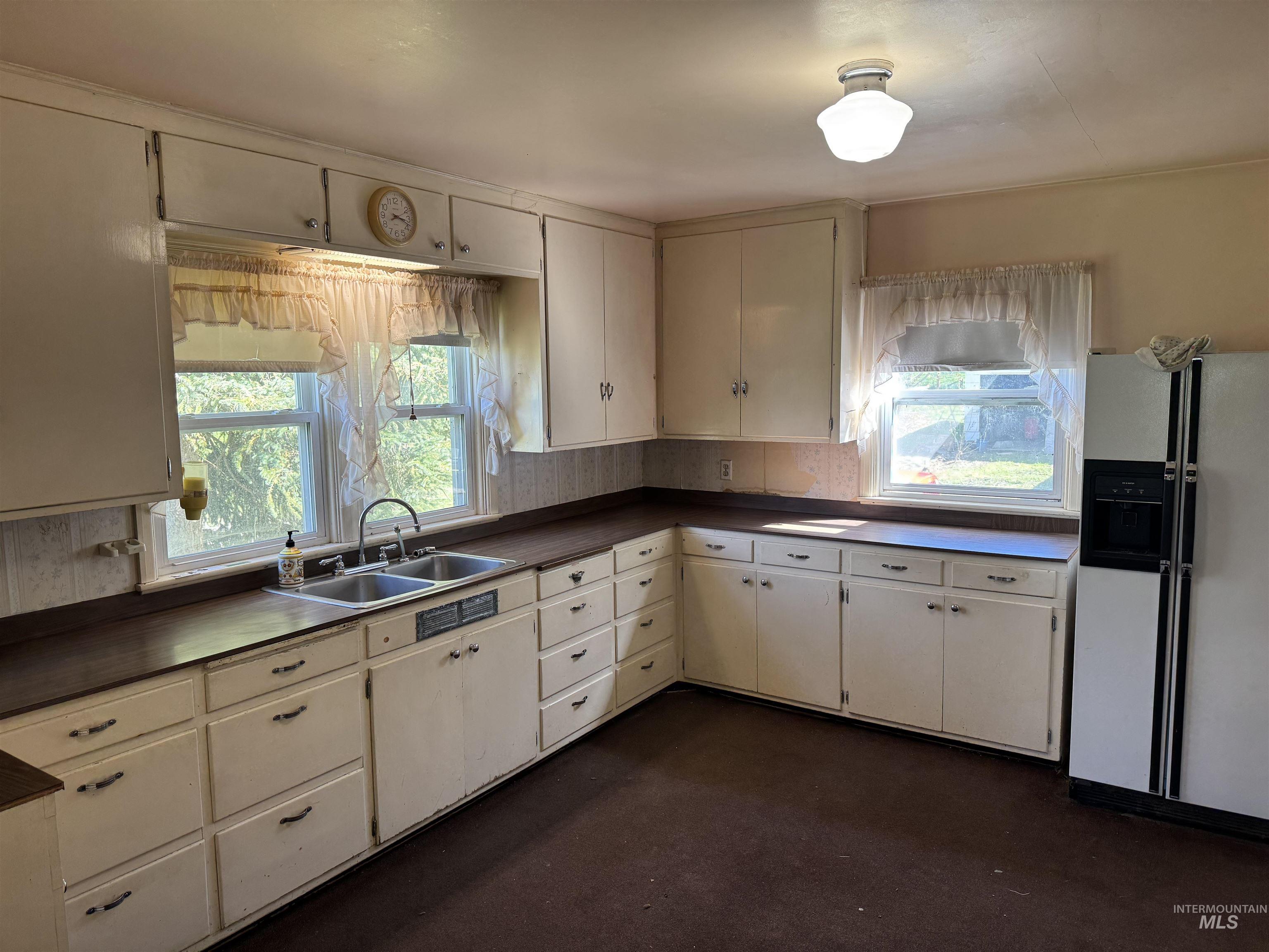 1109 3rd Street Kamiah, ID 83536 - Photo 8 of 21 Kitchen featuring white fridge with ice dispenser, dark countertops, and plenty of natural light