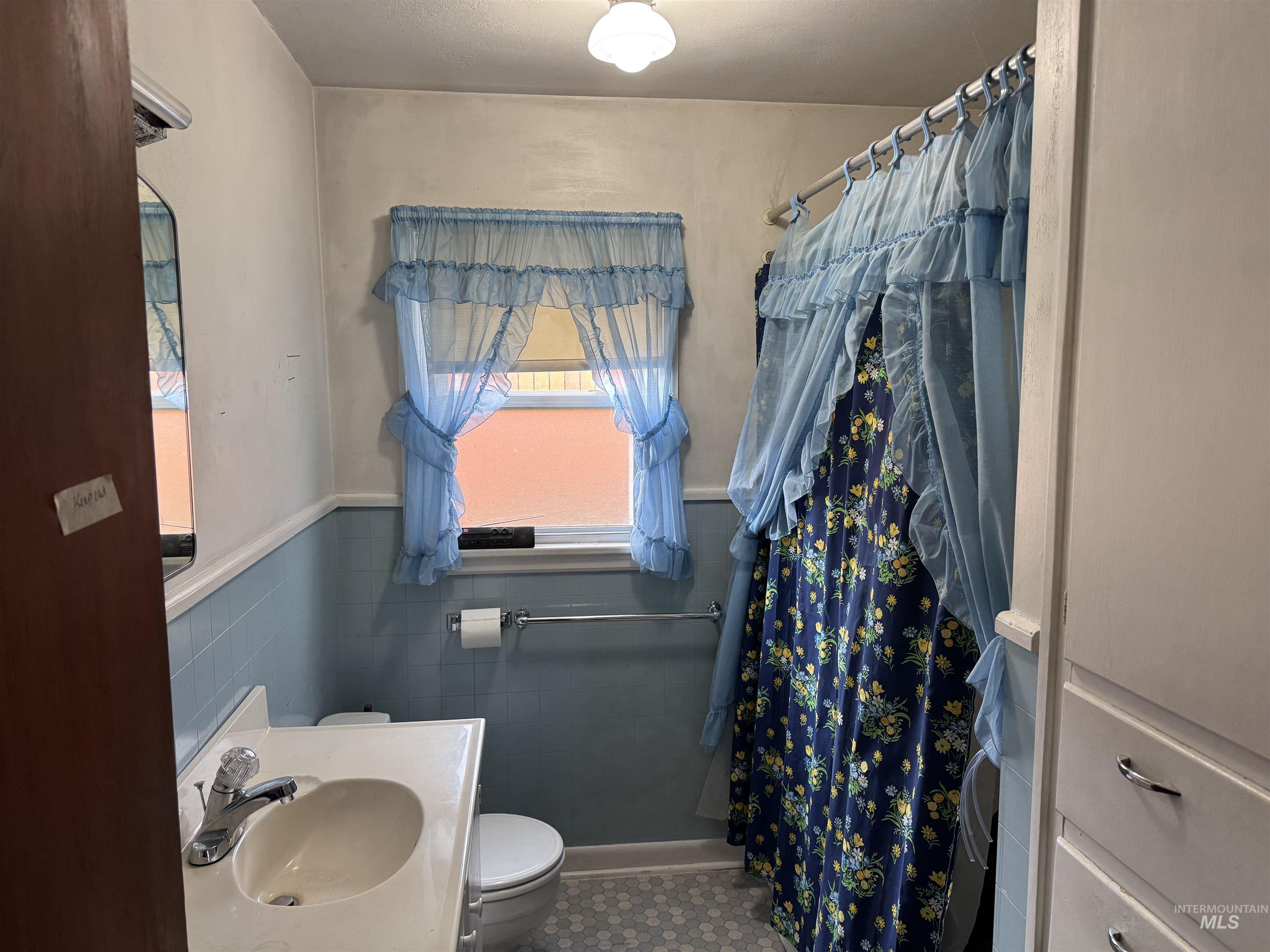 1109 3rd Street Kamiah, ID 83536 - Photo 10 of 17 Full bathroom with curtained shower, vanity, wainscoting, and tile walls