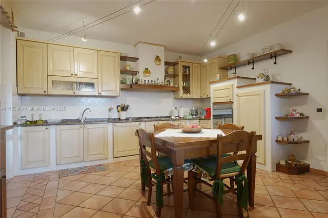 a kitchen with stainless steel appliances kitchen island granite countertop a table chairs sink and cabinets