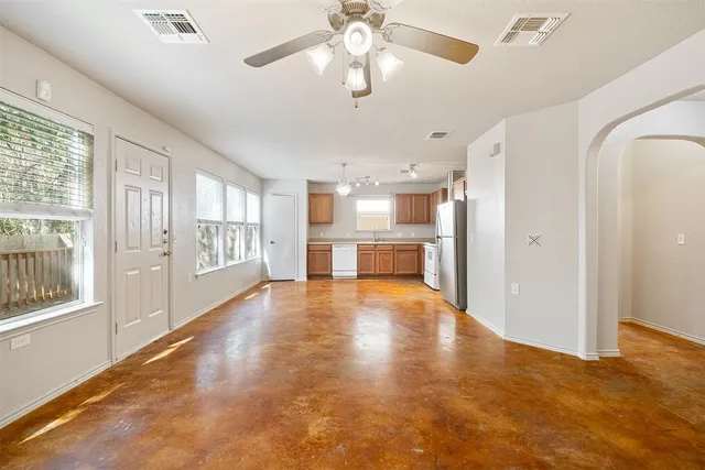 a view of an empty room with a window and kitchen view