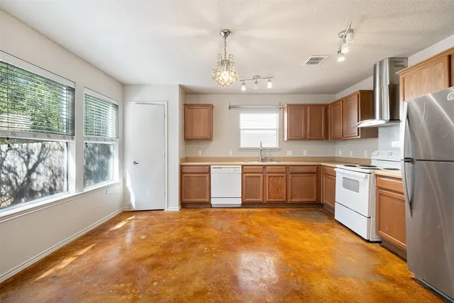 a kitchen with a refrigerator a sink dishwasher a stove and white cabinets with wooden floor