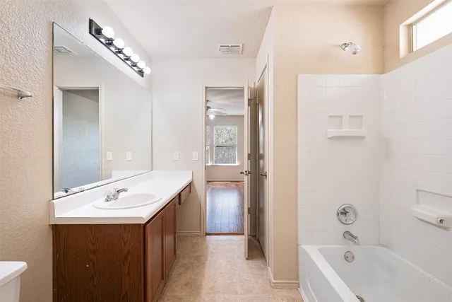 a bathroom with a tub a sink and mirror