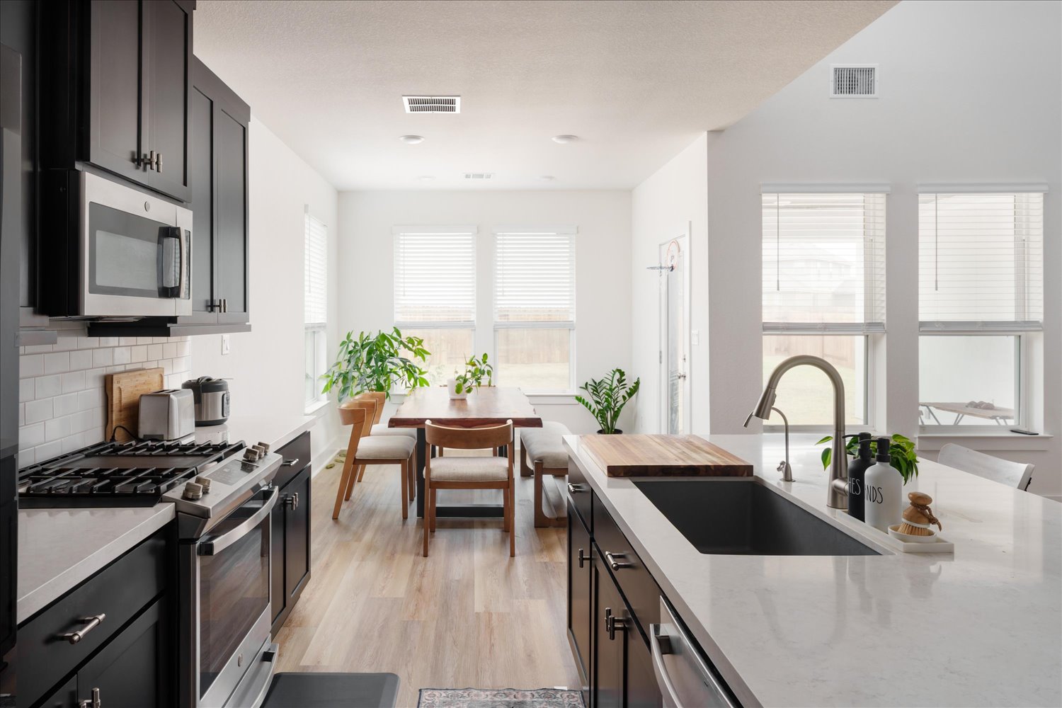 3120 Pale Rider Pass Leander, TX 78641 - Photo 12 of 34 Kitchen with stainless steel appliances, dark cabinets, light wood-style floors, tasteful backsplash, and light stone counters