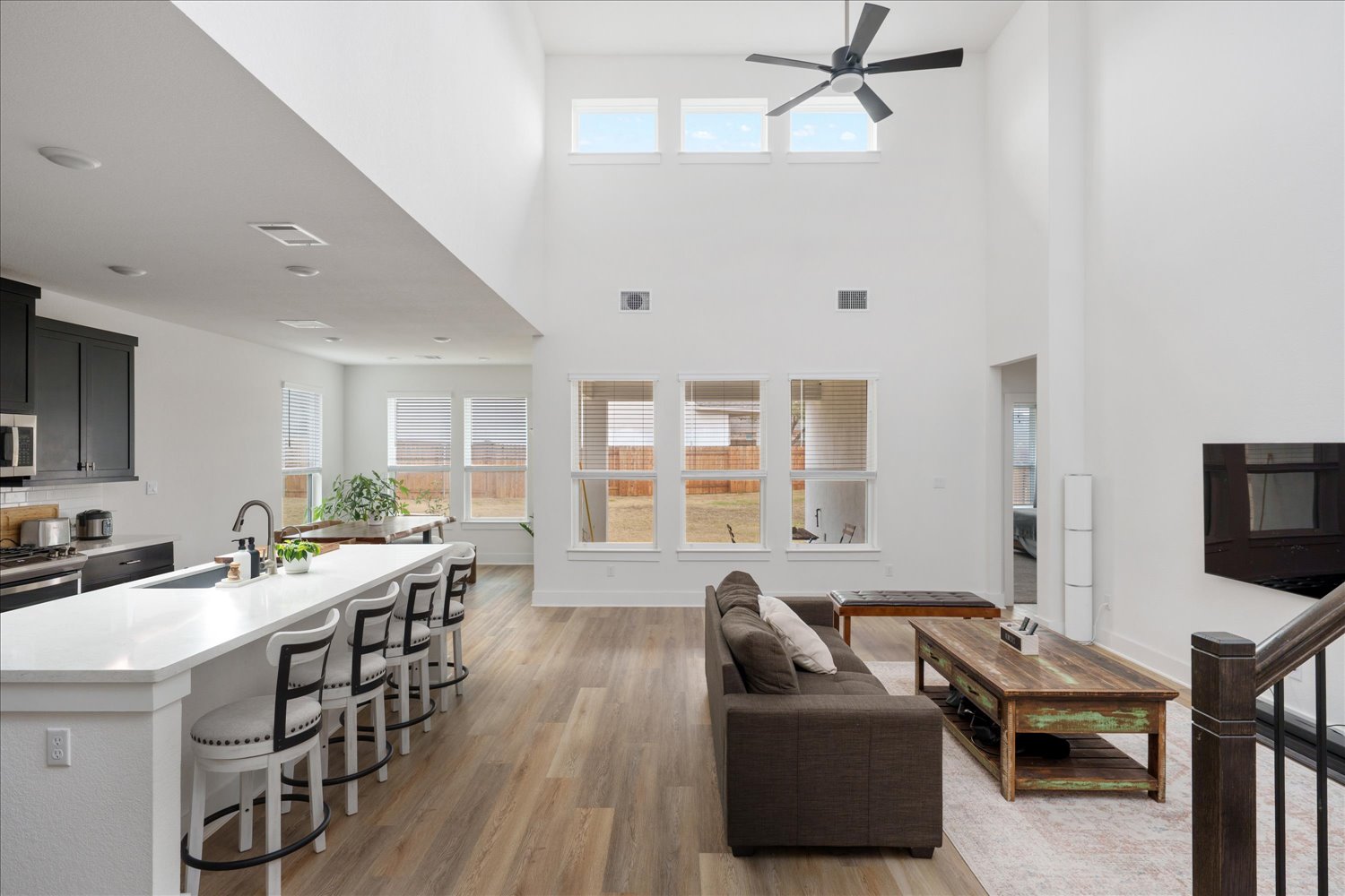 3120 Pale Rider Pass Leander, TX 78641 - Photo 7 of 34 Living area featuring light wood-type flooring, ceiling fan, and a high ceiling and windows