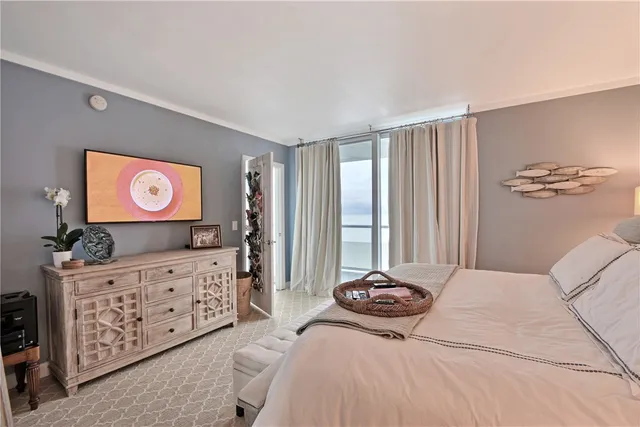 a bedroom with a bed flat screen tv and a large window