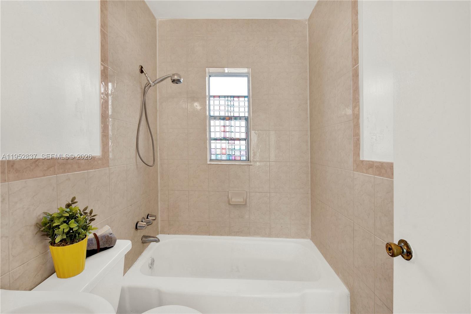 474 East 10th Street Hialeah, FL 33010 - Photo 13 of 38 a bathroom with a tub shower and a window