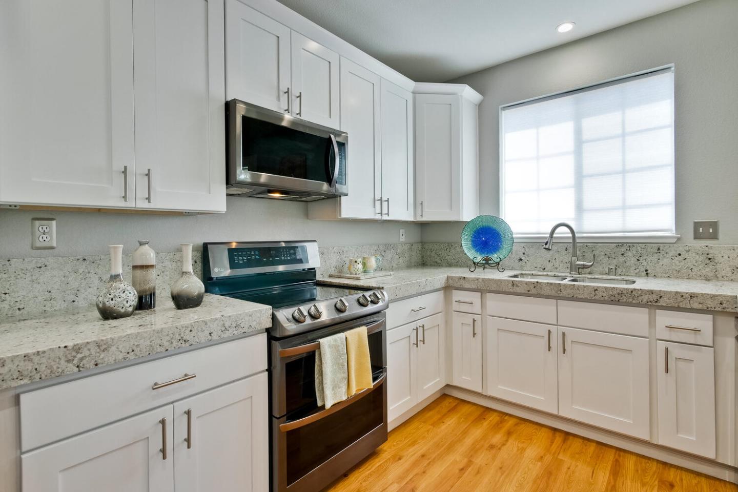 935 Old County Road, Unit 44 Belmont, CA 94002 - Photo 19 of 57 a kitchen with granite countertop a stove a sink and a white cabinets