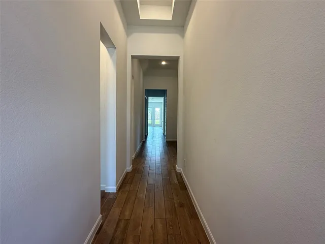 a view of a hallway with wooden floor and a bathroom