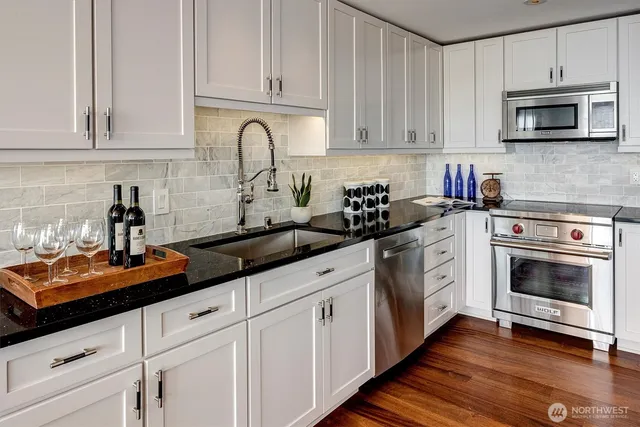 a kitchen with granite countertop white cabinets and stainless steel appliances