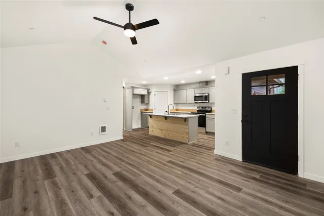 a view of kitchen with stainless steel appliances granite countertop a sink a stove and wooden floor