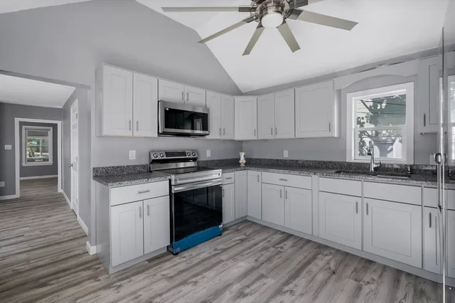 a kitchen with granite countertop a stove sink and microwave