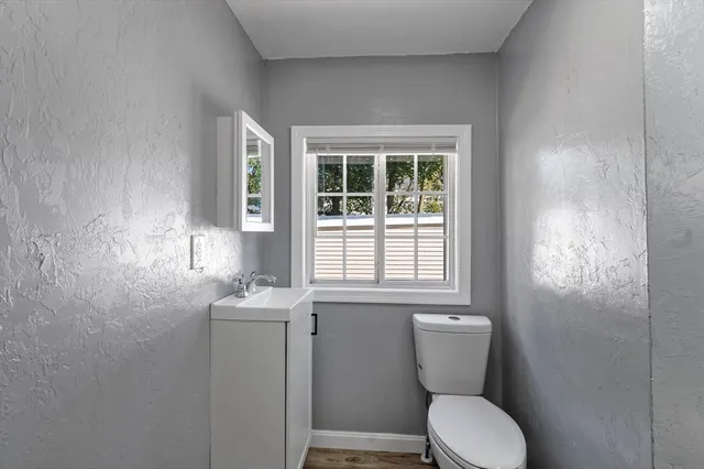 a bathroom with a toilet sink and mirror next to a window