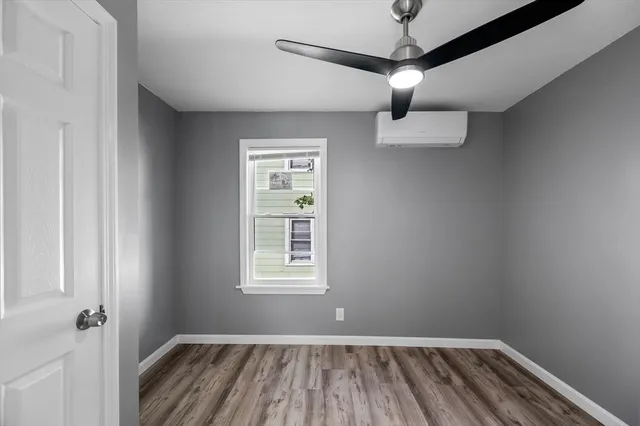 a view of empty room with wooden floor and fan