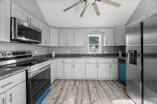 a kitchen with stainless steel appliances granite countertop a stove a sink and a microwave