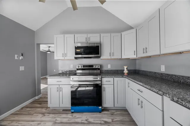 a kitchen with stainless steel appliances granite countertop a stove a sink and a microwave