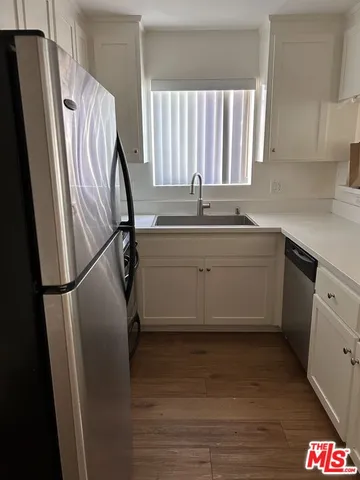 a kitchen with stainless steel appliances a refrigerator sink and wooden floor
