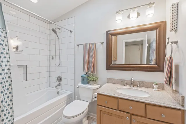 a bathroom with a granite countertop sink toilet a mirror a bathtub and shower