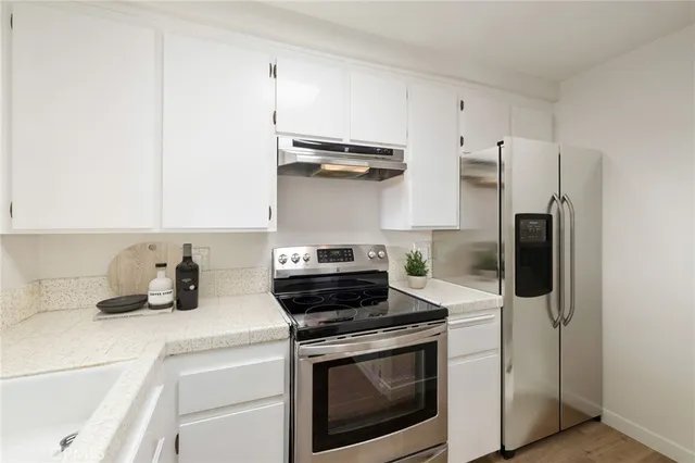 a kitchen with a refrigerator stove and white cabinets