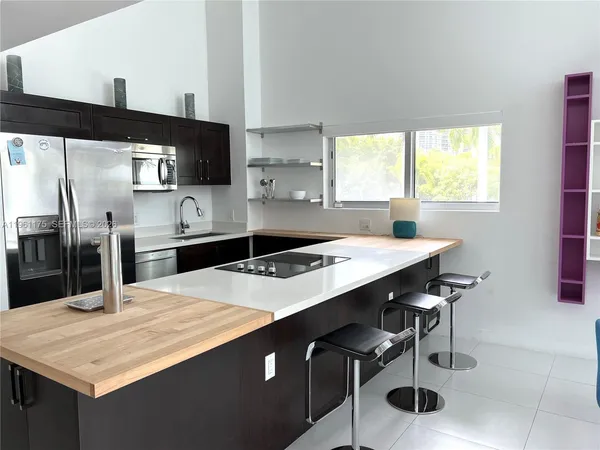 a kitchen with stainless steel appliances kitchen island granite countertop a sink and a refrigerator