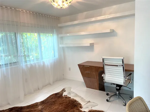 a view of a workspace with furniture and a window