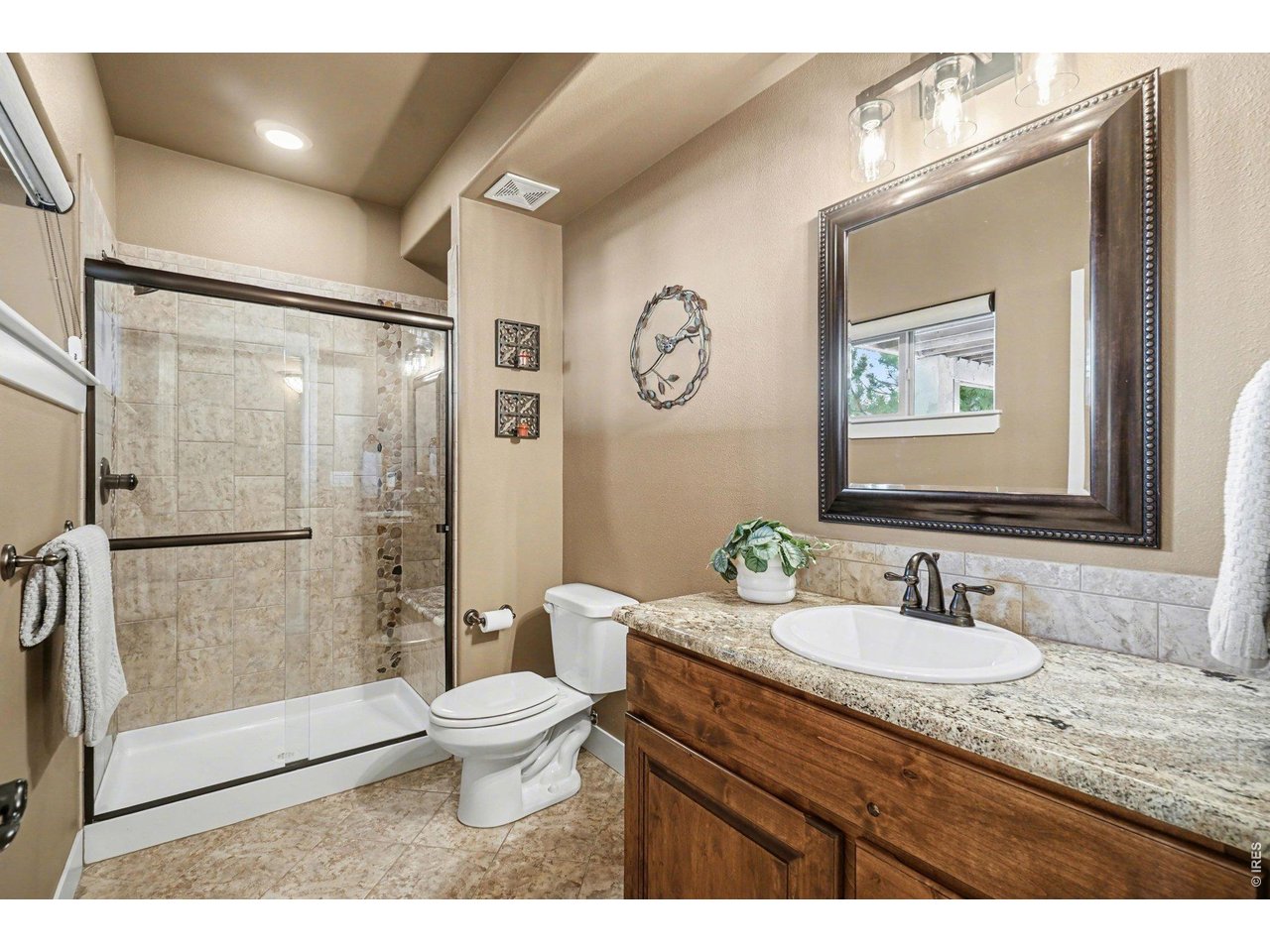 10723 Buckhorn Ridge Way Loveland, CO 80538 - Photo 32 of 50 a bathroom with a granite countertop sink a toilet a mirror and shower