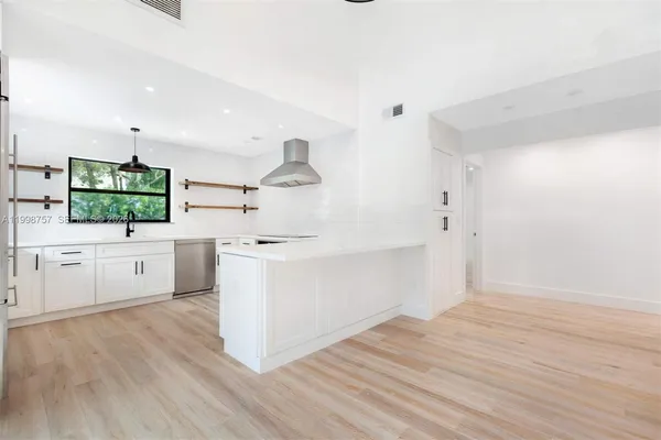a kitchen with white cabinets stainless steel appliances and window