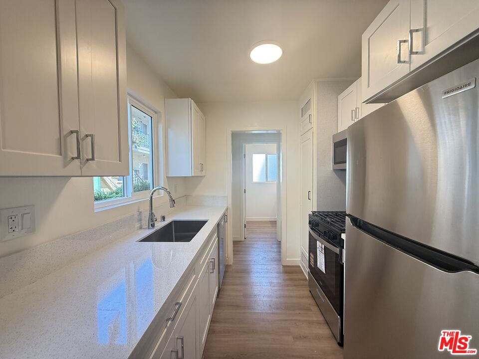 1314 10th Street, Unit A Santa Monica, CA 90401 - Photo 18 of 53 a kitchen with granite countertop a refrigerator a sink and wooden cabinets