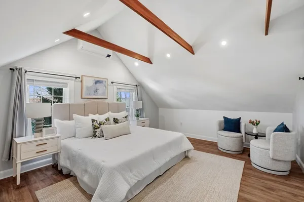 a bedroom with a large bed and wooden floor