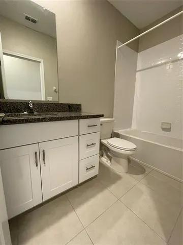 a bathroom with a granite countertop sink a toilet and a mirror