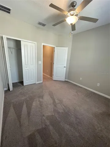 an empty room with closet and a ceiling fan