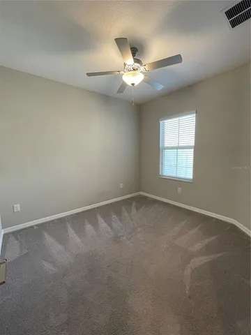 an empty room with a window and a fan