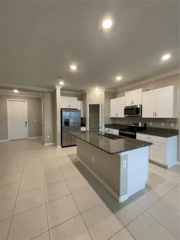 a large kitchen with stainless steel appliances kitchen island granite countertop a sink and cabinets
