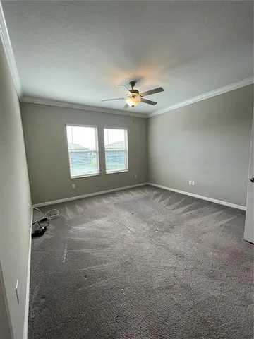an empty room with windows and ceiling fan