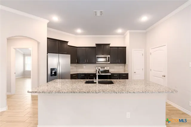 a kitchen with stainless steel appliances granite countertop a sink a stove and a refrigerator