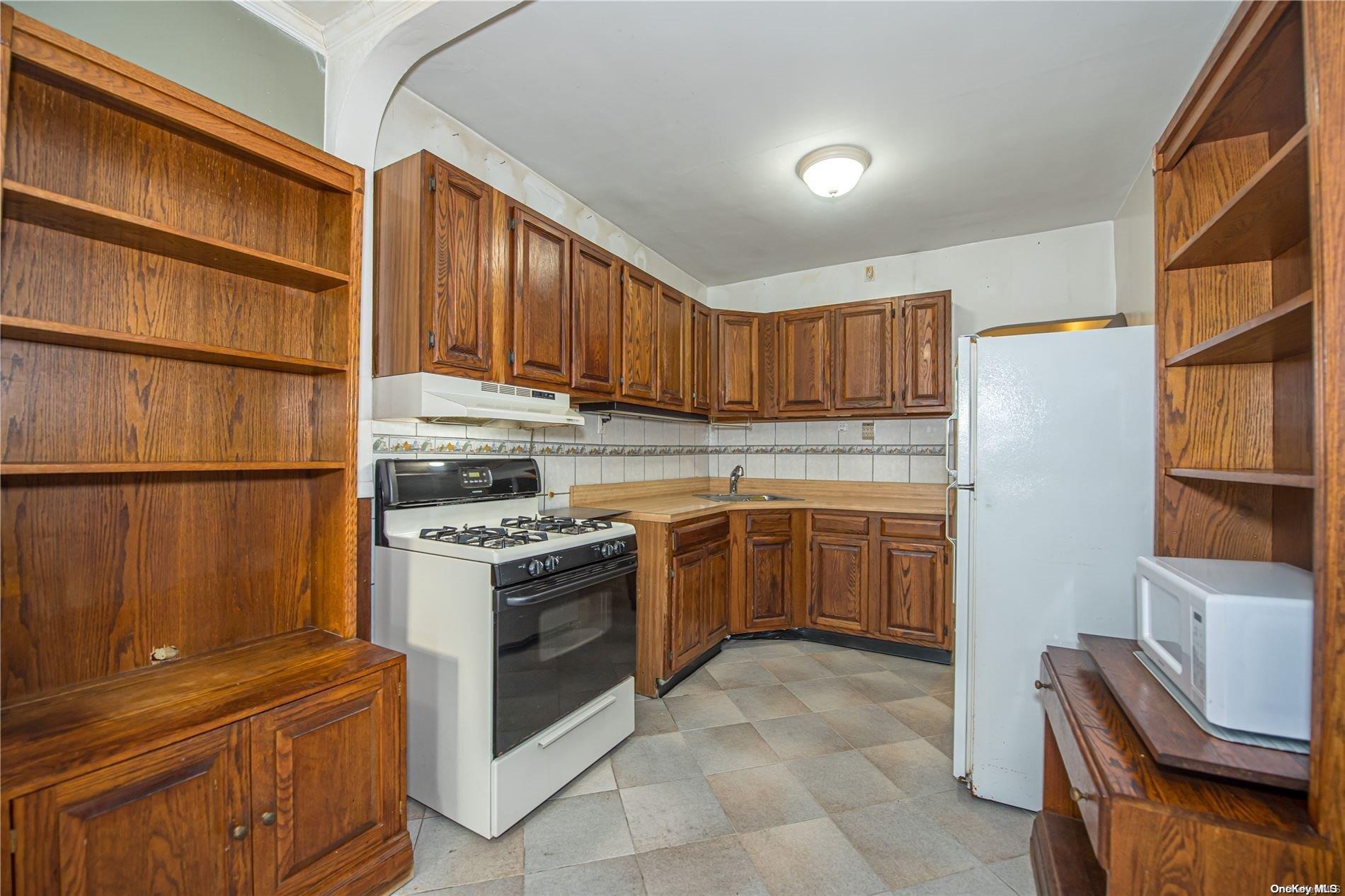 53-15 37th Road Queens, NY 11377 - Photo 7 of 25 a kitchen with a stove top oven sink and a refrigerator