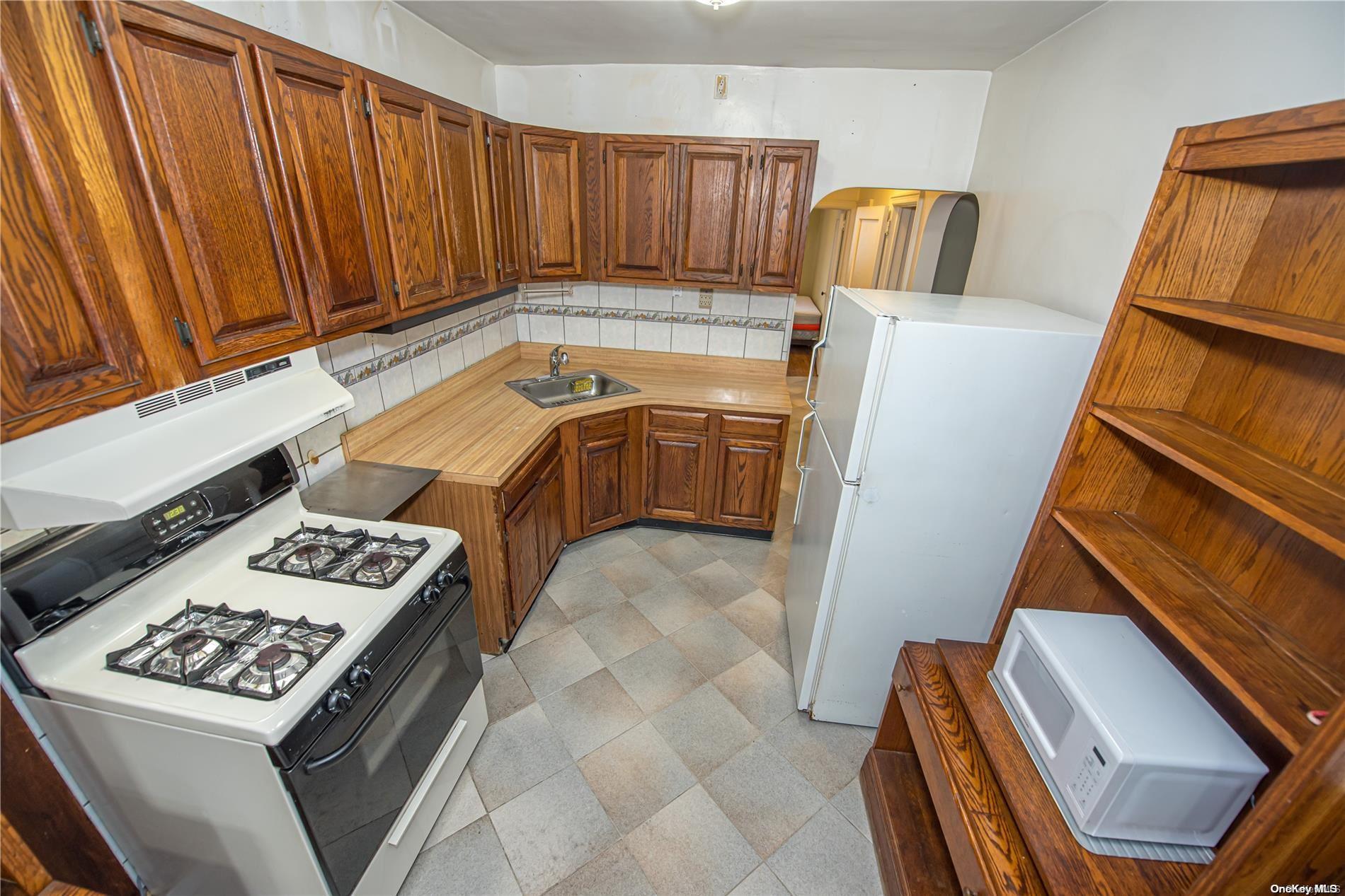 53-15 37th Road Queens, NY 11377 - Photo 10 of 25 a kitchen with a stove and a refrigerator