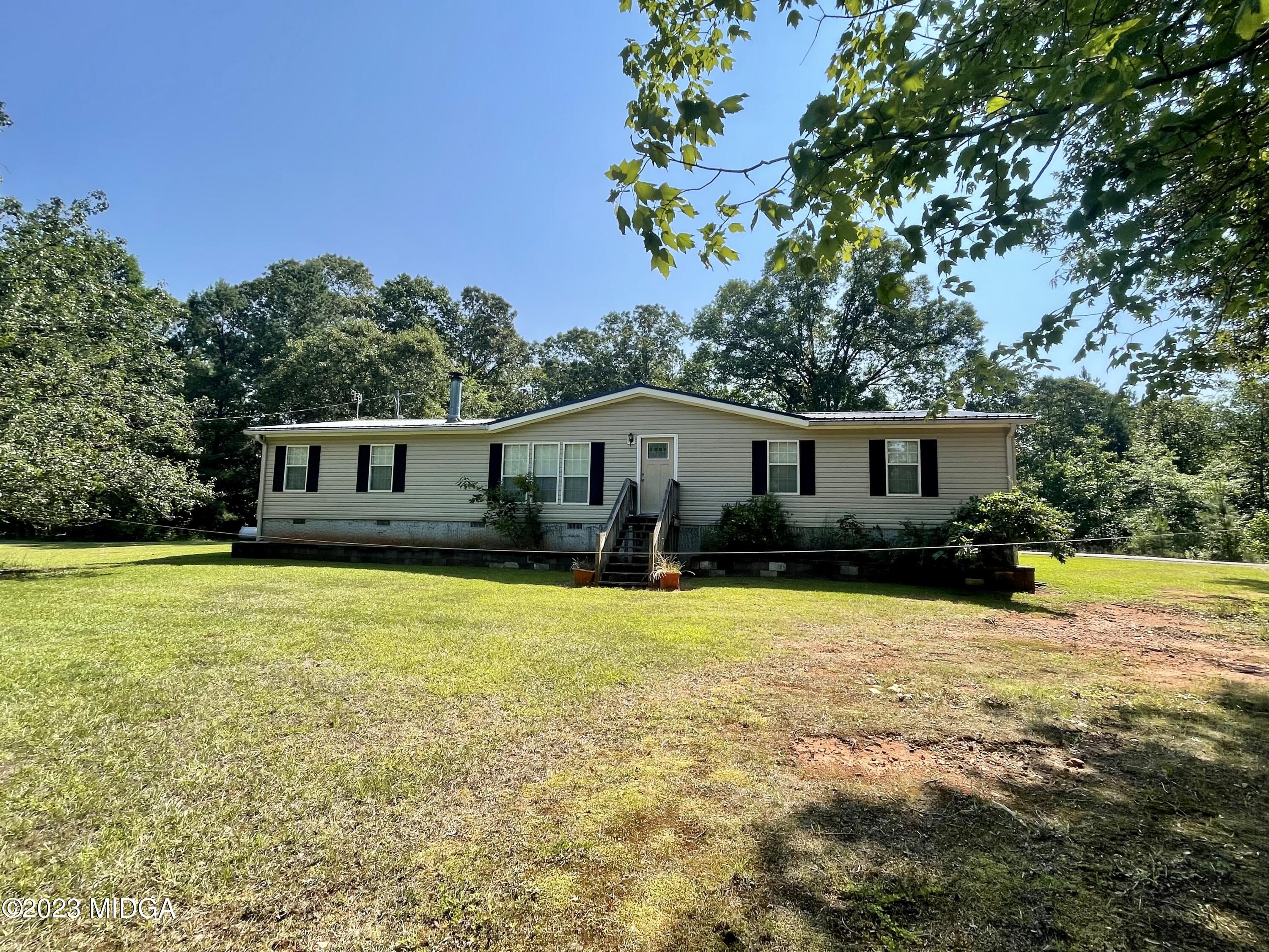 1222 Lassiter Road Forsyth, GA 31029 - Photo 1 of 6 a front view of house with yard and trees in the background