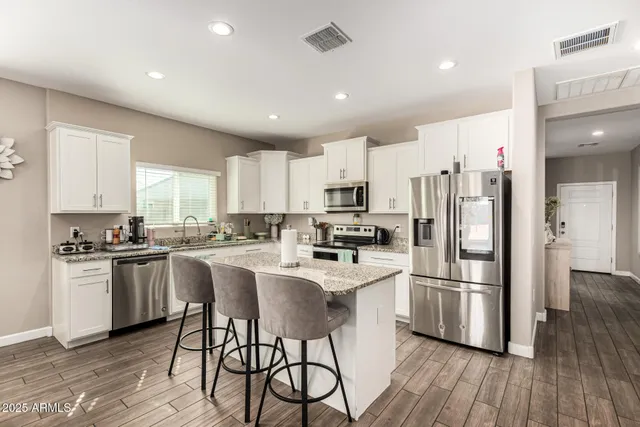 a kitchen with stainless steel appliances a refrigerator a stove a sink dishwasher and a refrigerator with wooden floor