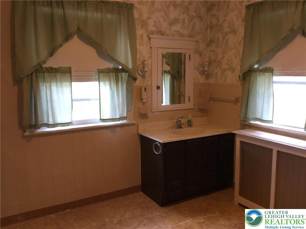 1105 Main Street Slatington, PA 18080 - Photo 15 of 31 A well-maintained bathroom with tiled walls and vanity, illuminated by natural light from two windows.