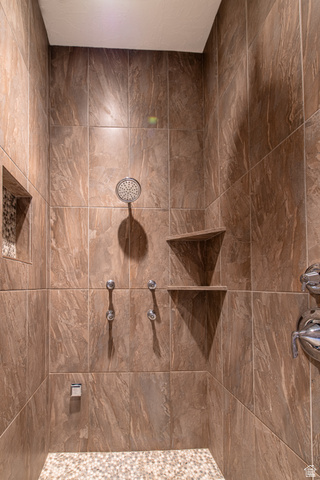 322 340 E Street Ivins, UT 84738 - Photo 30 of 61 Shower with large format brown-toned wall tiles, a rainfall showerhead, multiple body sprays, a built-in corner shelf, and a mosaic pebble floor