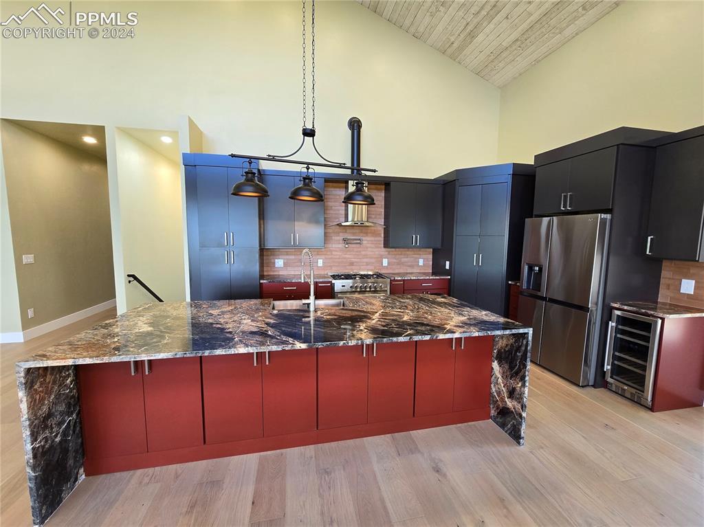 33036 Meadow Ridge Lane Trinidad, CO 81082 - Photo 18 of 50 Kitchen featuring a large island with sink, backsplash, wine cooler, hanging light fixtures, and appliances with stainless steel finishes