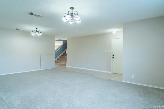 a view of an empty room with a chandelier fan