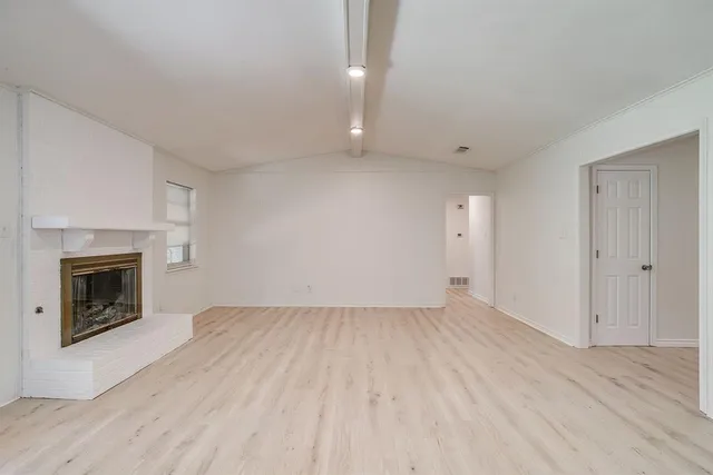 an empty room with wooden floor and fireplace