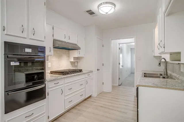 a kitchen with granite countertop white cabinets and stainless steel appliances