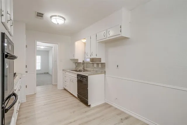 a view of a kitchen with a sink and dishwasher a refrigerator with wooden floor